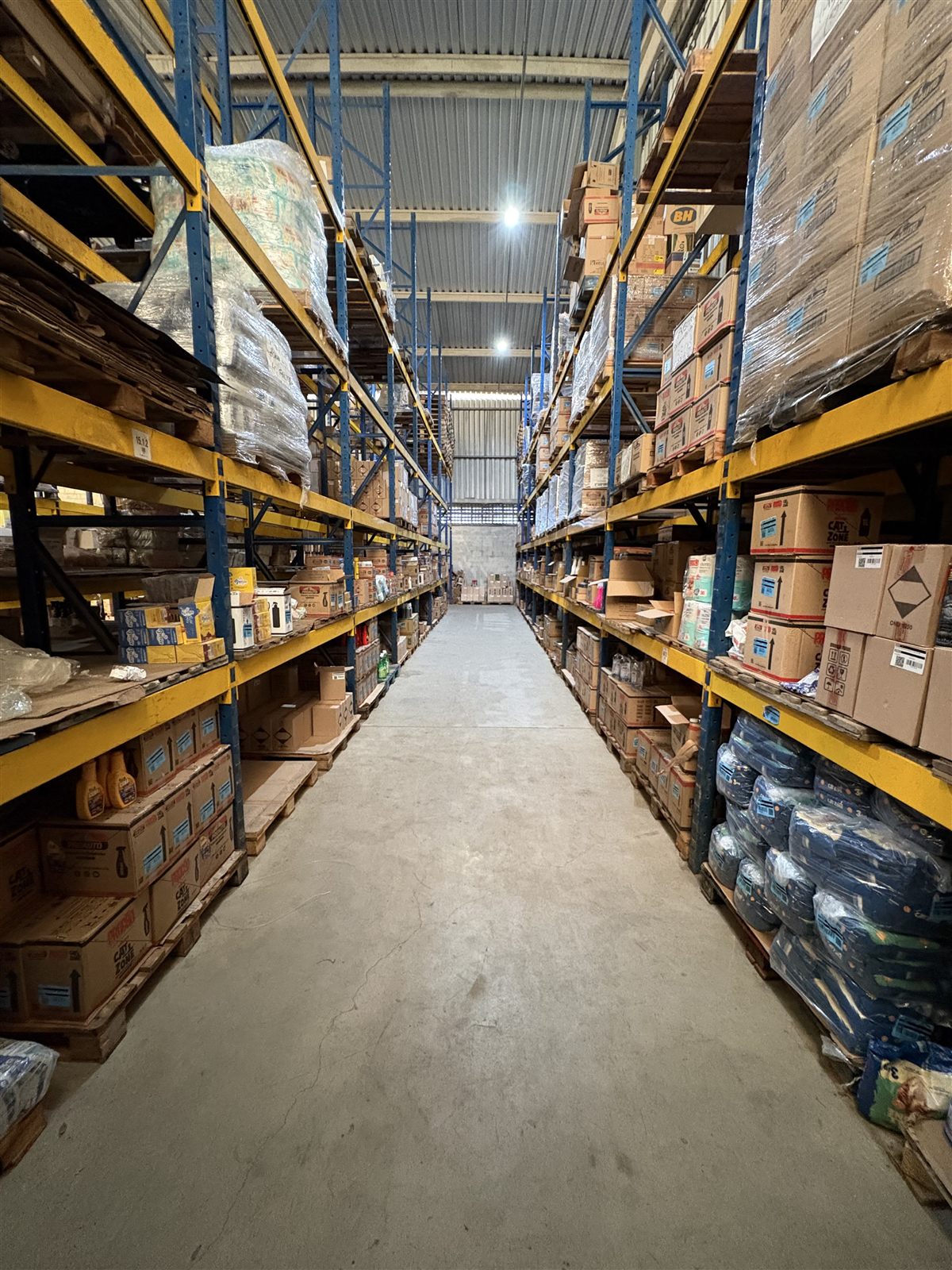 Corredor do estoque da Dbosco, com mercadorias organizadas em porta-paletes